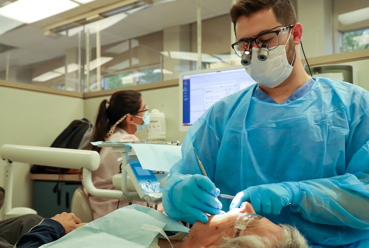dental student examining a man's mouth 
