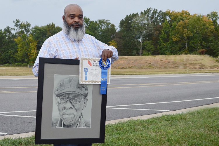 Artist John H. Smith holding graphite pencil drawing and award ribbon