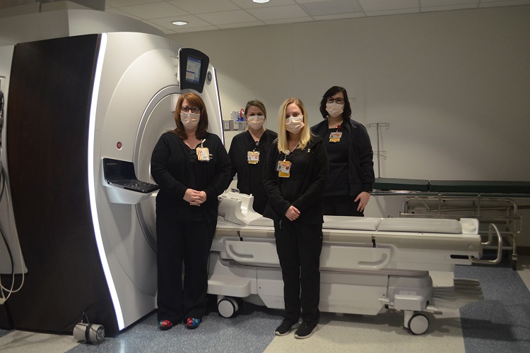MRI techs Amanda Blalock-Bowen, Tessa Howerton, Brooklyn Rooker and Katelyn Daniel stand next to an MRI machine.