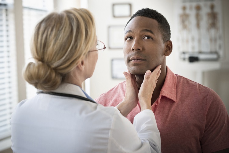 African-American male patient having neck examined by White female doctor