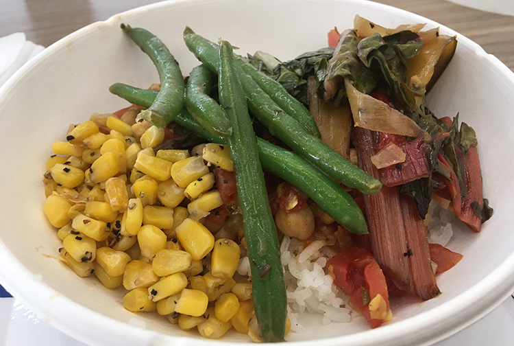A bowl of corn, green beans and swiss chard on a bed of rice.