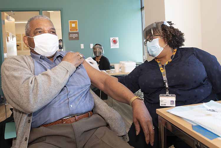 Kimberly Battle vaccinates her father, Phillip Battle, at the VCU Health Hub at 25th