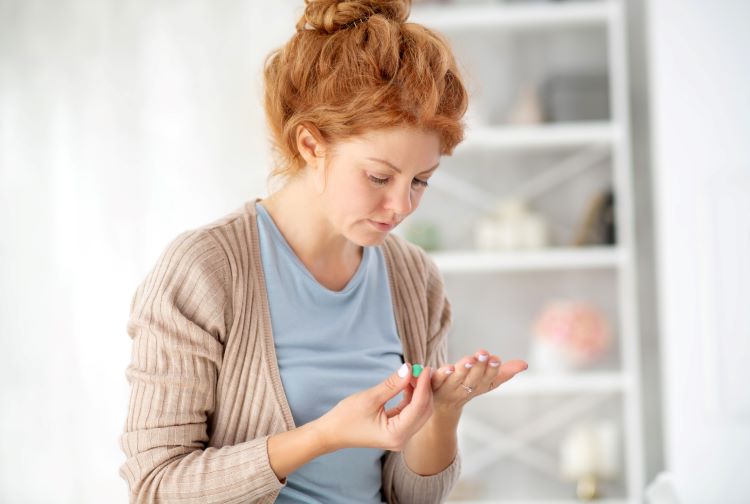 Woman looking at pills in her hand