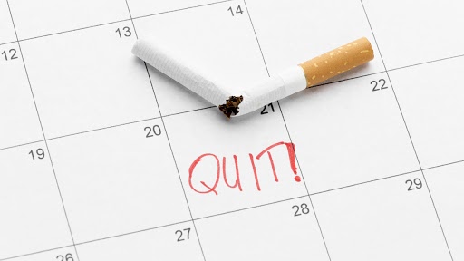A calendar with a broken cigarette on top and the word "Quit" "