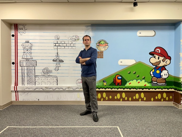 Brent Fagg in front of a video game themed mural he painted 