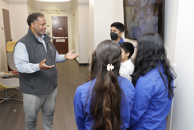 Man speaking with teenagers in a lab.