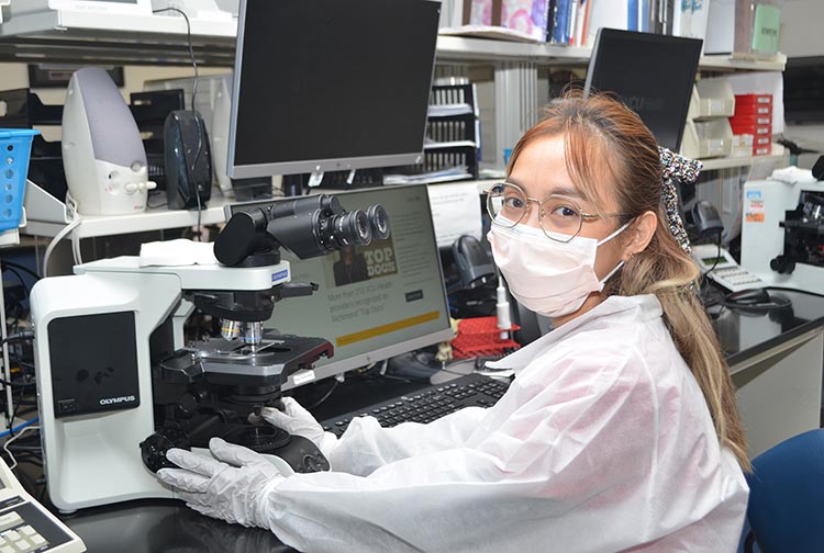A lady works with a microscope in a hospital laboratory.