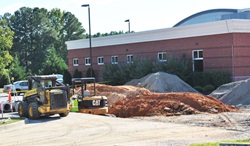 construction vehicles and dirt piles outside a brick building.