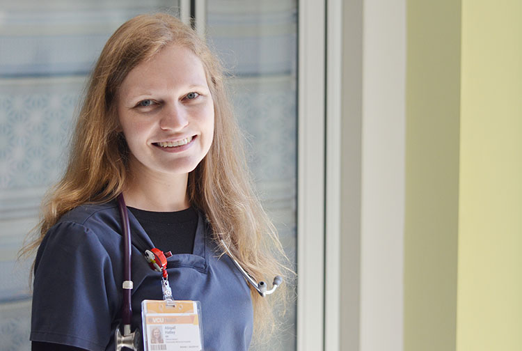 A nurse stands in front of a patient room.