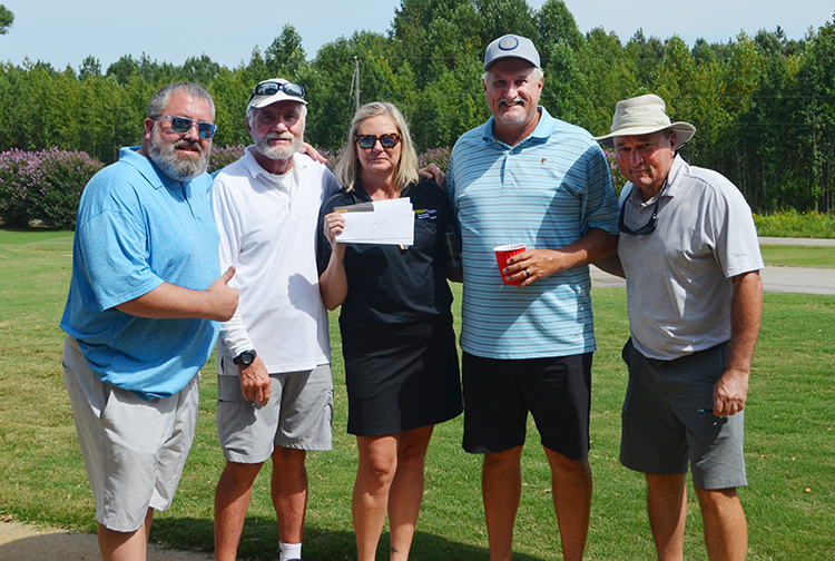 A lady awards four men with a prize on a golf course.