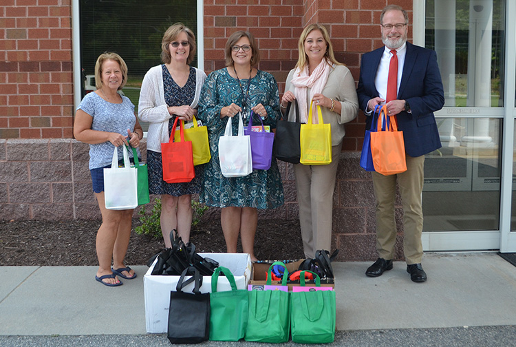 A group of health care workers and teachers hold goodie bags outside a cancer center.