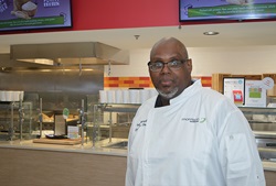 a chef stands in front of a hospital cafeteria serving line