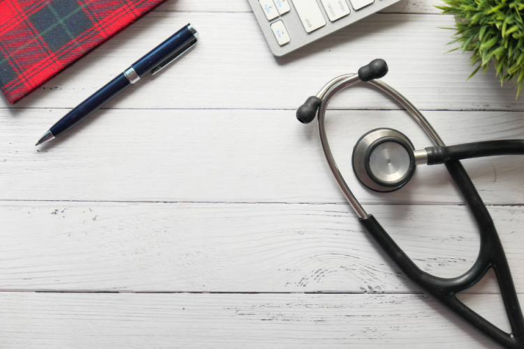 Image of a stethoscope next to a pen and keyboard