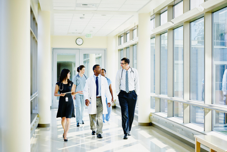 A group of health providers walking in a bright, sunlit hallway.