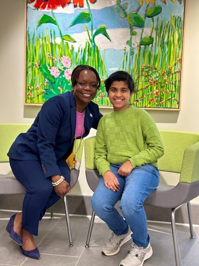 Pediatric patient Zoe smiles with Jeniece Roane, MS, RN, vice president of operations at CHoR. Zoe is wearing a lime green sweater.