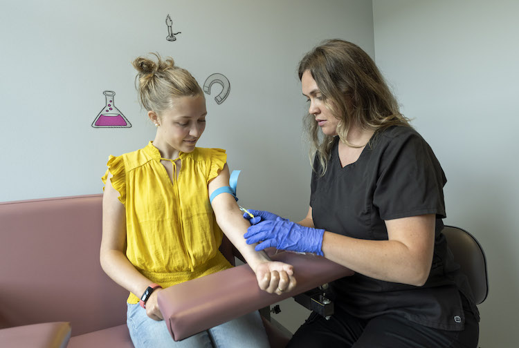 A teenage girl prepares to have blood drawn from a clinical research nurse coordinator.