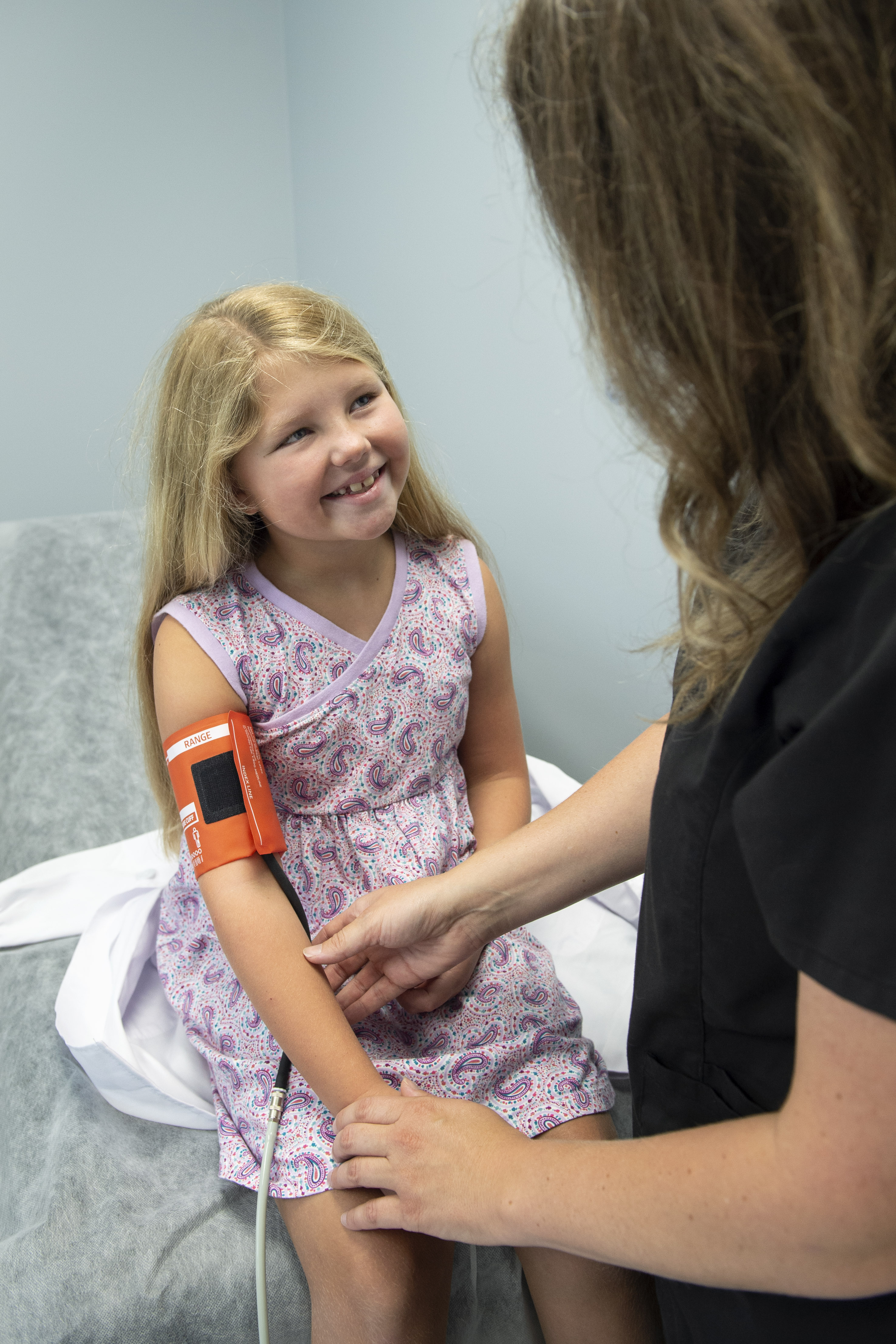 Little girl smiles at nurse while getting her blood pressure taken