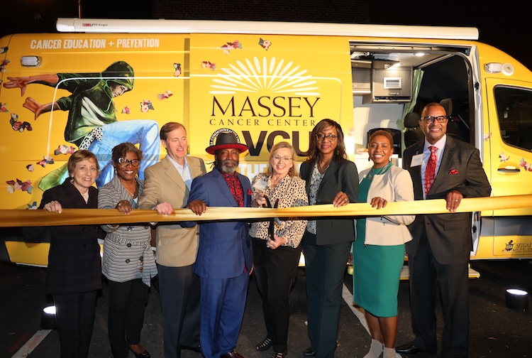 Group of people standing in front of a van for a ribbon cutting ceremony