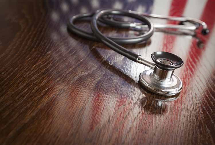 Stethoscope atop the reflection of an American flag on a desk