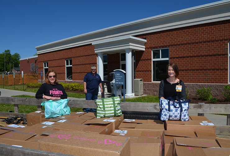 Penny Evans and friends holding special bag of goodies, surrounded by boxes of donations.