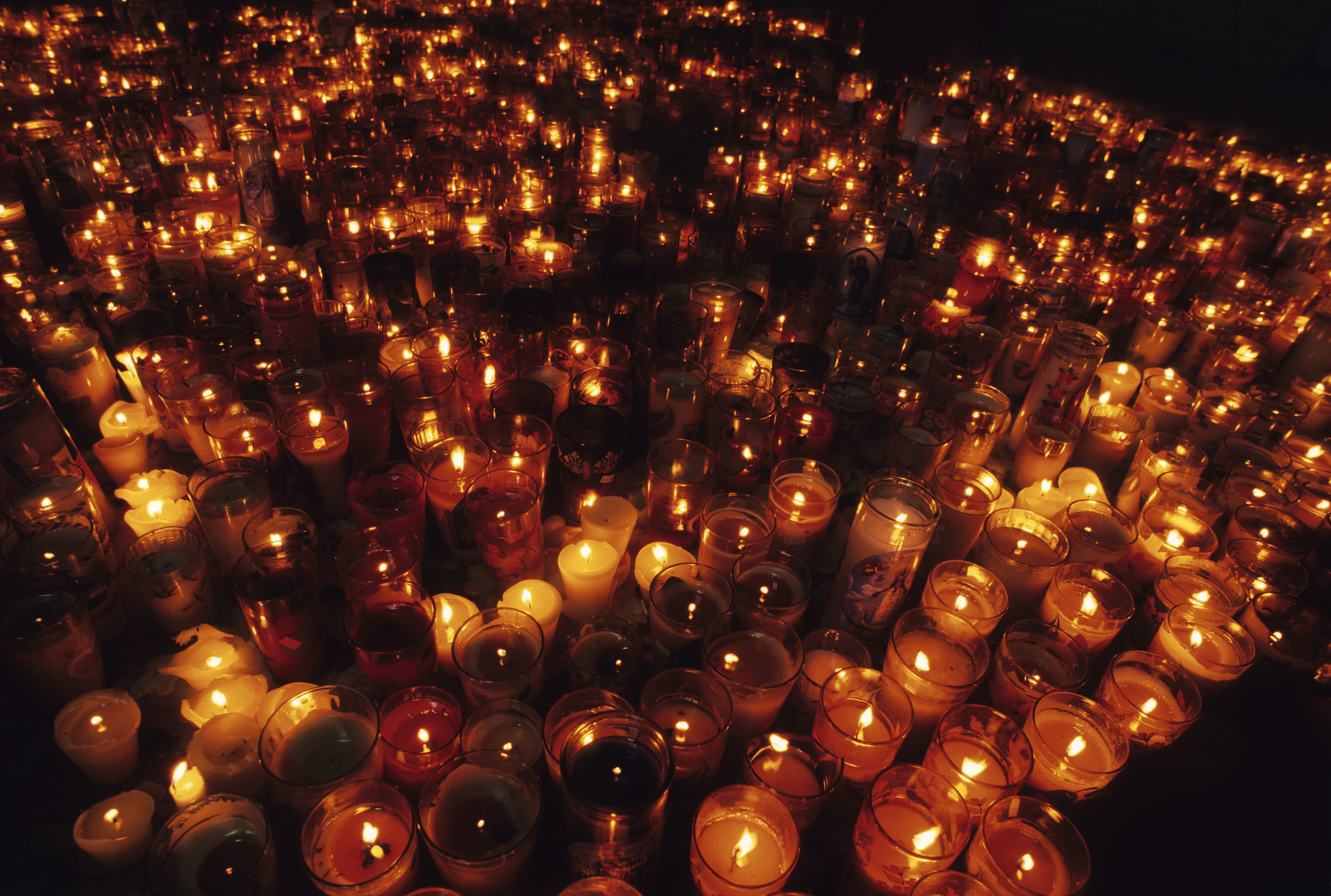 Numerous lit candles in a dark space