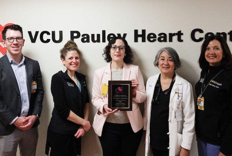Members of the cardio-oncology team stand in front of a VCU Pauley Heart Center sign. 