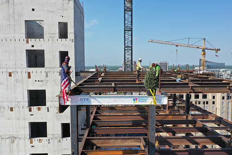 Workers plant an American flag on a steel beam during the CHoR Children's tower topping out ceremony.