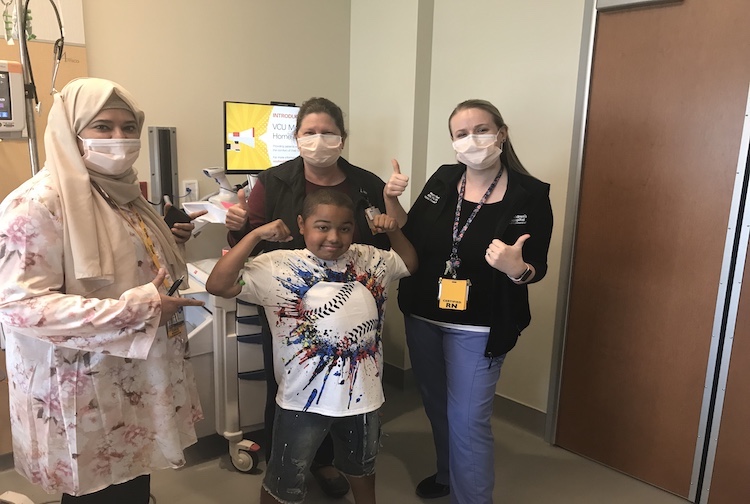 Little boy stands by three women who are part of the Children’s Hospital of Richmond at VCU’s care and research team.