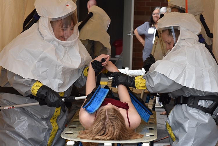 Children in hazmat suits practicing lifesaving skills.