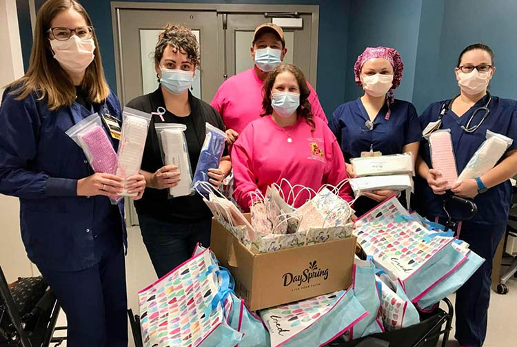 A group of people pose with care bags in a hospital
