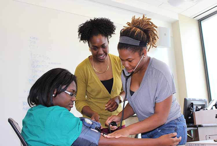 Two Black female medical students checking a patient's blood pressure