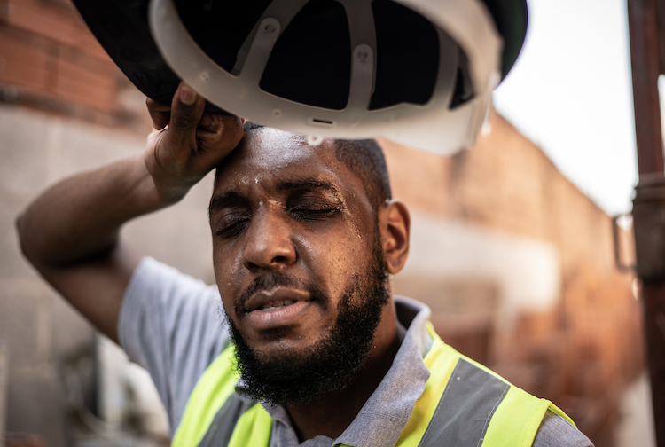 Exhausted construction worker wiping sweat off of his face.