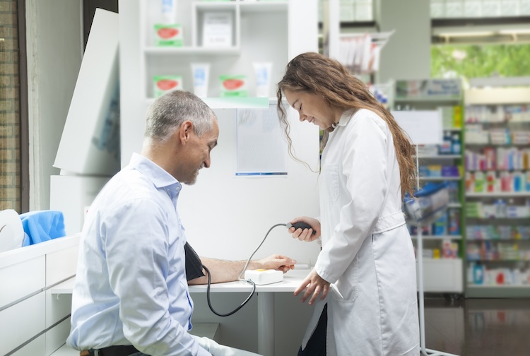 female pharmacist taking the blood pressure of an older man