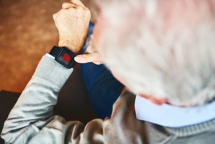 Older man looks at the a fitness tracker he is wearing on his left hand. 