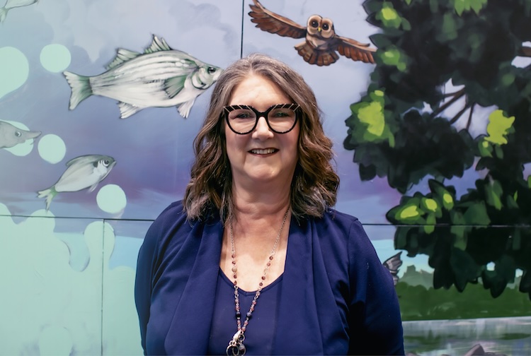Woman smiling in front of an animal mural backdrop