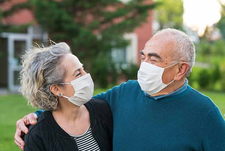Older adult couple with masks holding each other