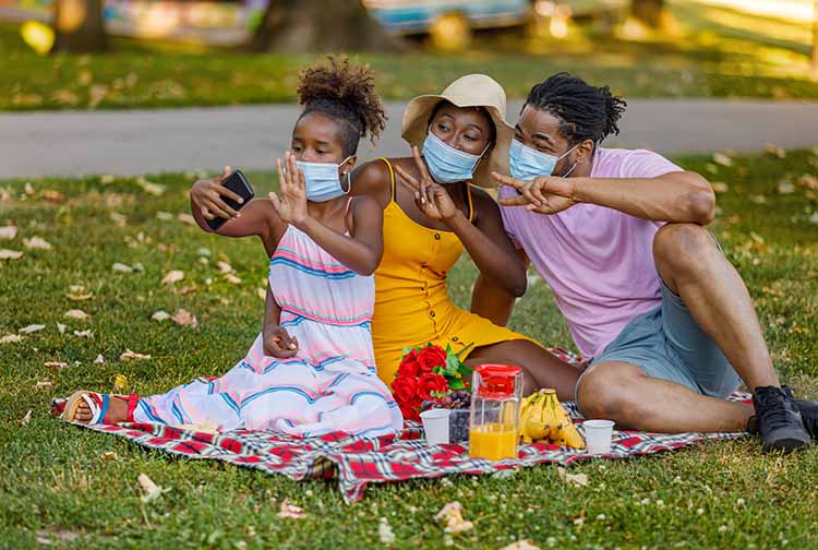 Family wearing masks having a picnic