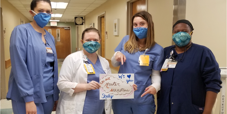Medical team wearing mask, holding thank-you card
