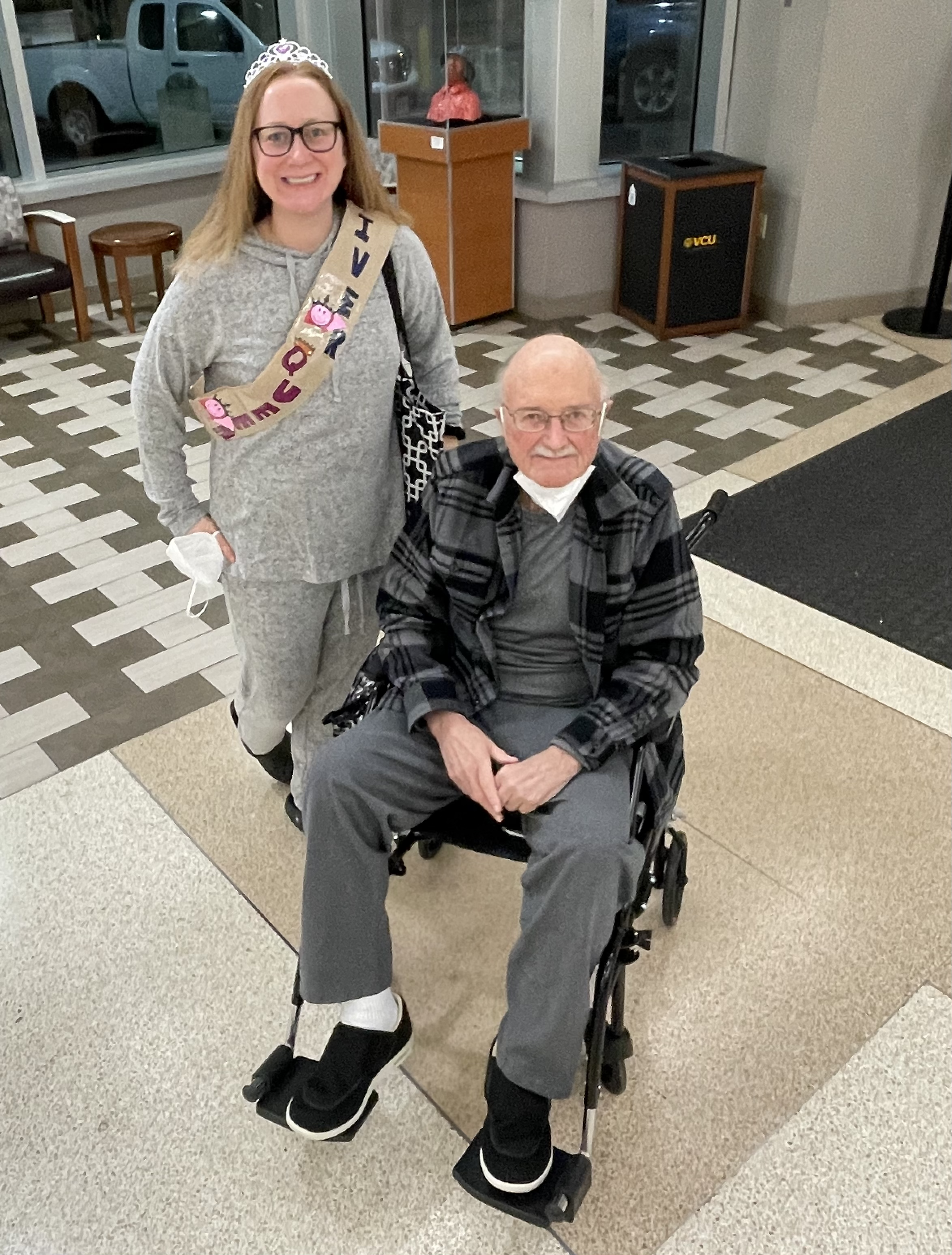 Man in wheelchair and woman with tiara smiling