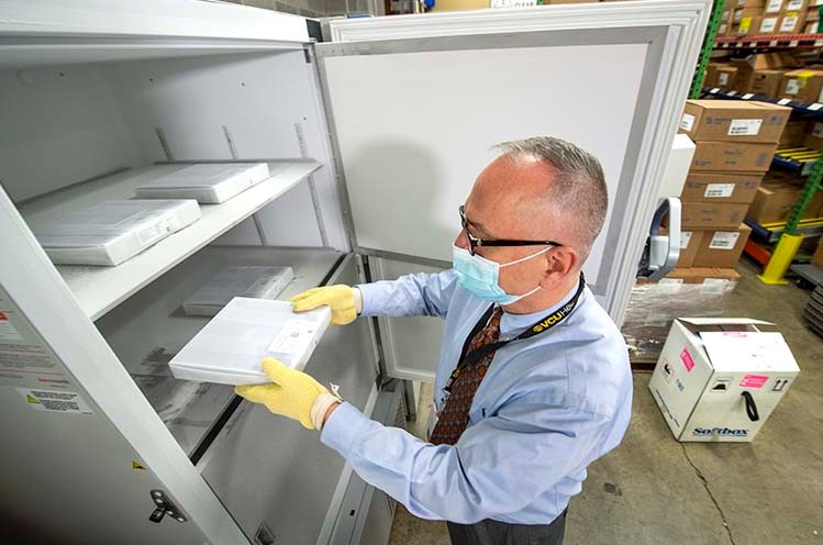 Rodney Stiltner places trays of vaccine in the ultra-cold freezer.