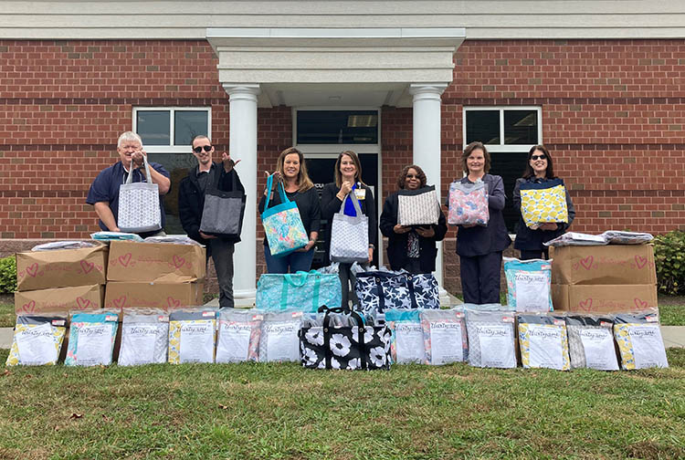 A group of people with 200 cancer care bags outside a brick building