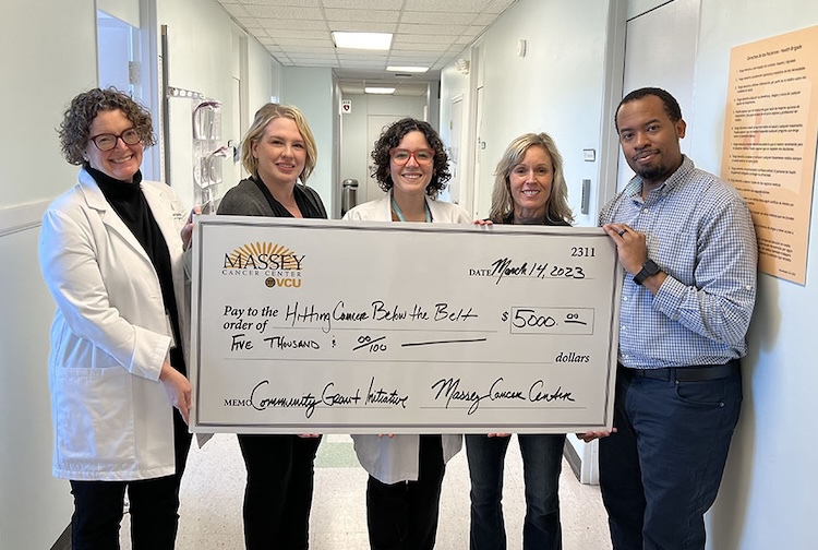 "five people standing together in a hallway with a large check from Massey Comprehensive Cancer Center"