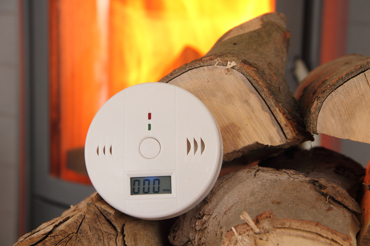 A CO detector in front of a burning fireplace