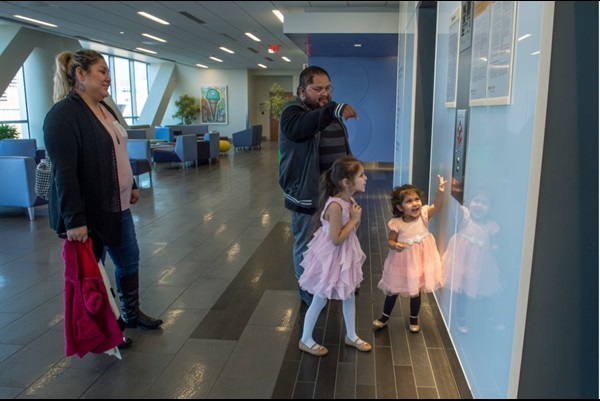 Roxana Sanchez and Jorge Cubas assist their daughters, from left, Astrid Cubas-Sanchez and Roxanne Cubas-Sanchez as they call for an elevator at the Children’s Pavilion following a recent appointment. (Photo by Kevin Morley, University Relations)