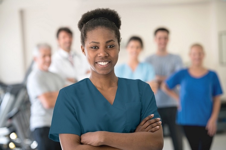 African-American female nurse smiling in front of diverse group of men and women
