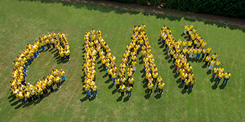 People standing on grass spelling out the letters CMH