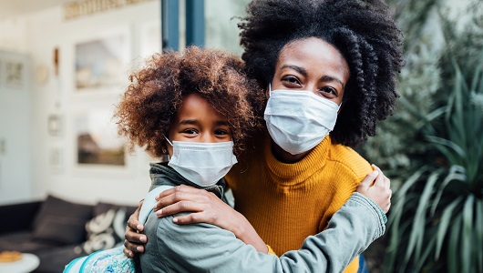 African-American mother and daughter wearing masks and hugging