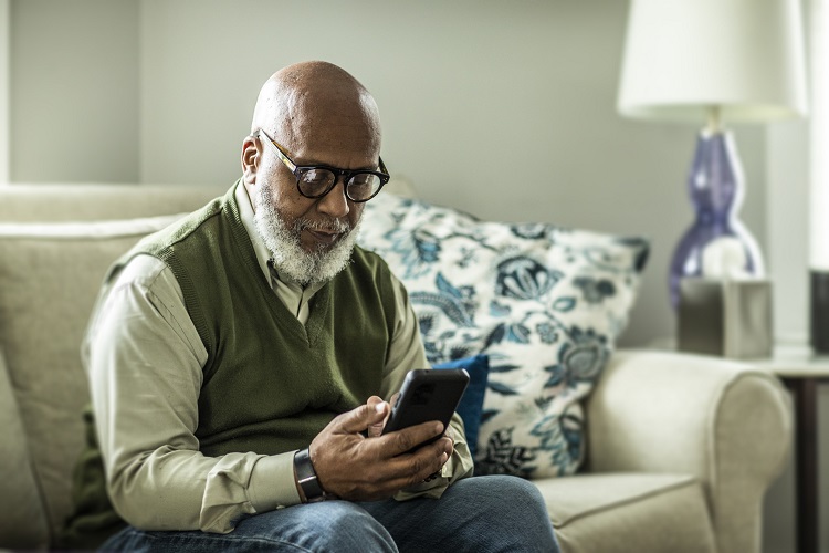 Older male sitting on couch looking at cell phone