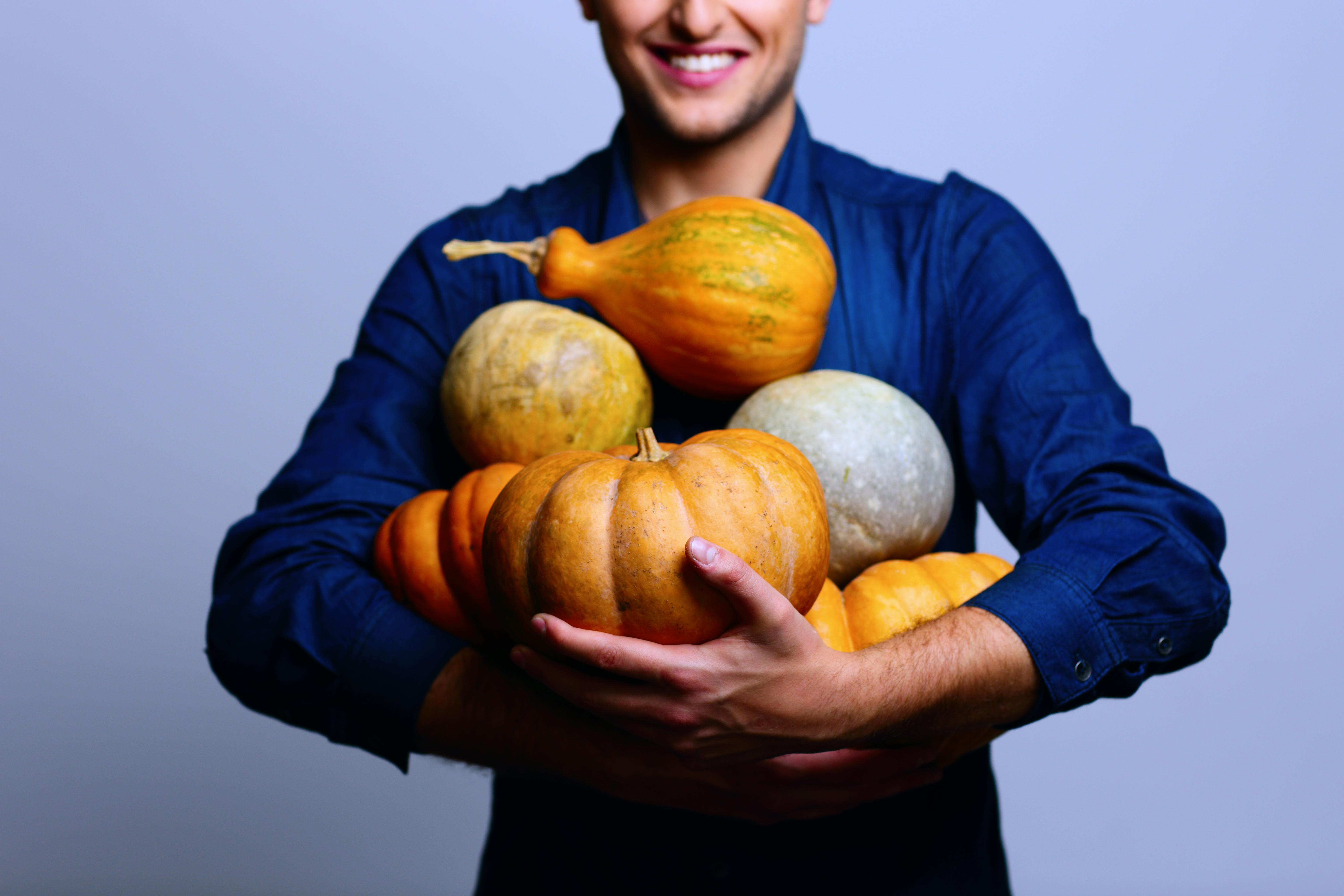 Man holding armful of pumpkins and squash
