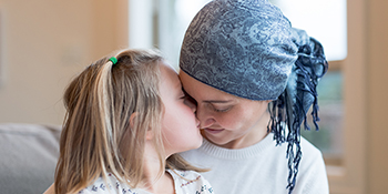 Child showing affection and kissing cancer patient's nose